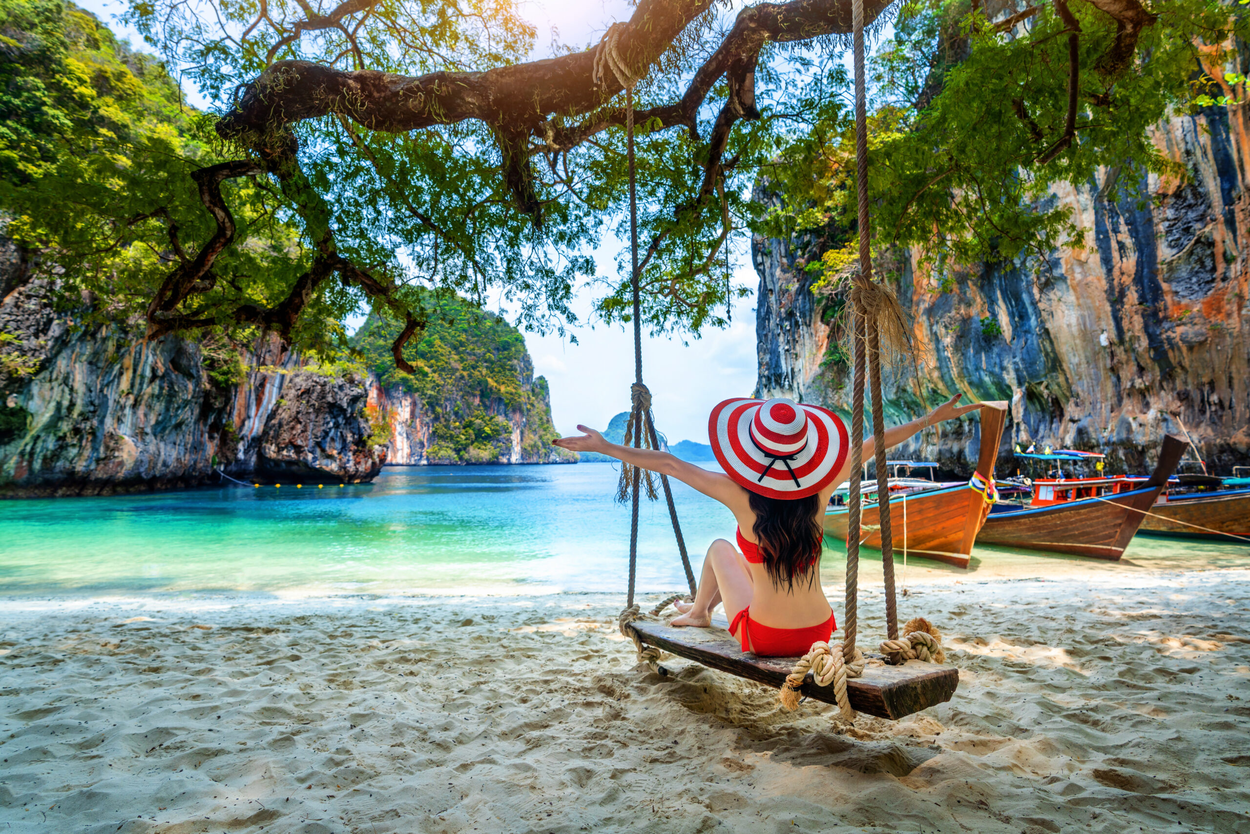 Woman in bikini relaxing on swing at Ko lao lading island, Krabi, Thailand.